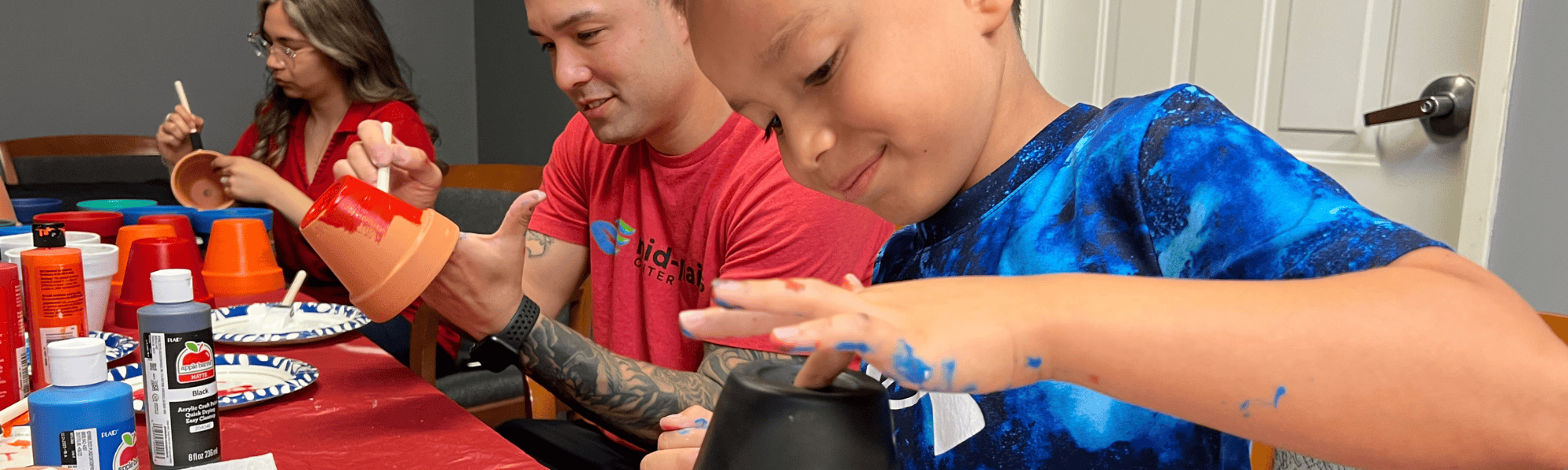A father and son volunteer to paint flower pots during Day of Action 2025.