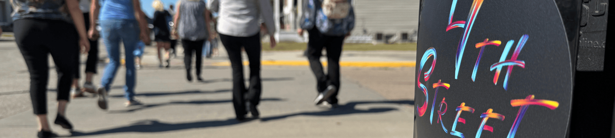 Blurred people walk past a 4th Street-branded garbage can.