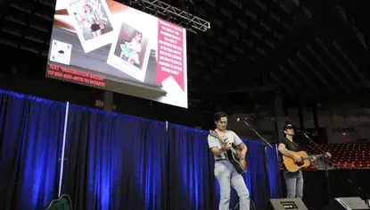 The Talbott Brothers play in front of a child's testimonial on a big screen talking about the importance of Dolly Parton's Imagination Library.