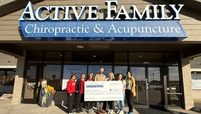 Active Family Chiropractic and Acupuncture and Heartland United Way staff hold a giant check.