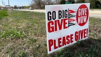A Go Big GIVE sign stands near a road in Aurora in 2025.